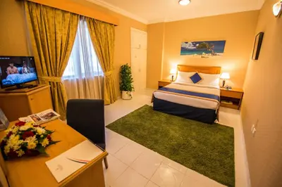 a hotel room with a bed and a television at Welcome Hotel Apartments 1 in Dubai