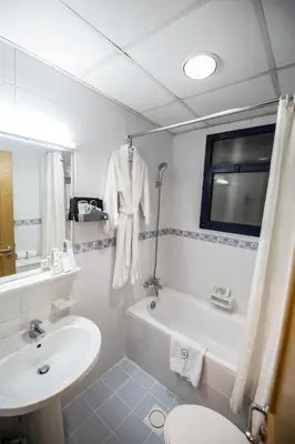 a bathroom with a sink and a tub and a toilet at Welcome Hotel Apartments 1 in Dubai