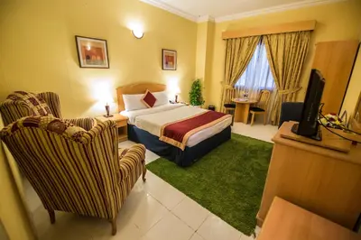 a hotel room with a bed and a tv and chairs at Welcome Hotel Apartments 1 in Dubai
