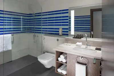 a bathroom with a toilet and a sink and a shower at Naumi Hotel Dubai in Dubai