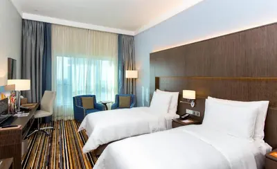 a hotel room with two beds and a desk at Naumi Hotel Dubai in Dubai