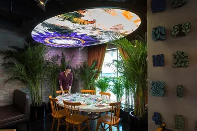a man standing at a table in a room with plants at Naumi Hotel Dubai in Dubai