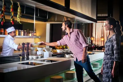 a man and woman standing in a kitchen preparing food at Centro Barsha - by Rotana in Dubai
