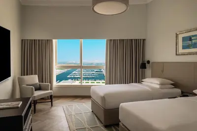a hotel room with two beds and a large window at Dubai Marriott Harbour Hotel And Suites in Dubai