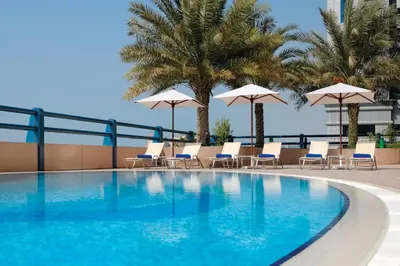 a swimming pool with chairs and umbrellas on a building at Dubai Marriott Harbour Hotel And Suites in Dubai