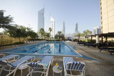 a swimming pool with chairs and a table in front of a building at The Apartments, Dubai World Trade Centre in Dubai