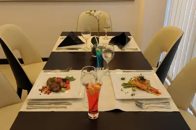 a table with two plates of food and wine glasses at The Apartments, Dubai World Trade Centre in Dubai