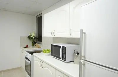a kitchen with white cabinets and a microwave at The Apartments, Dubai World Trade Centre in Dubai