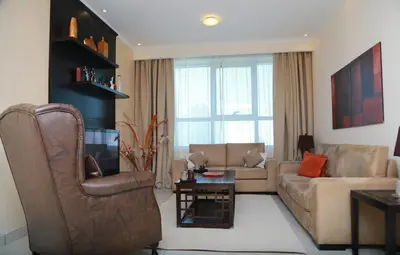 a living room with a couch and a chair at Armada Living - Holiday Homes Rental in Dubai