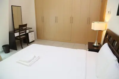 a bedroom with a white bed with a lamp and a desk at Armada Living - Holiday Homes Rental in Dubai