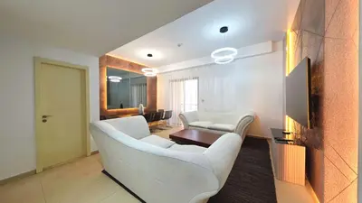 a living room with two white chairs and a television at Elan Rimal Suites in Dubai