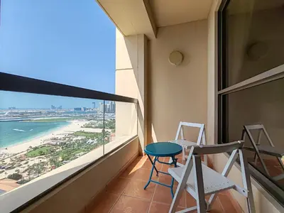 a balcony with chairs and a table and a view of the beach at Elan Rimal Suites in Dubai