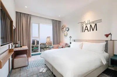 a hotel room with a bed and a large window at Rove Bur Dubai - Healthcare City in Dubai