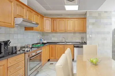 a kitchen with wooden cabinets and a table with a sink at Roda Beach Resort in Dubai