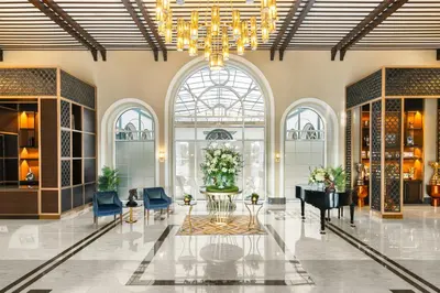 a lobby with a grand piano and blue chairs at Al Habtoor Polo Resort in Dubai