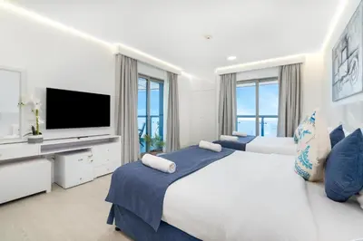 a white bedroom with a large bed and a flat screen tv at Princess Tower Dubai Marina private Spa amazing view in Dubai