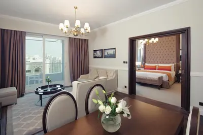a living room with a room with a bed and a table at Dukes The Palm Dubai Hotel in Dubai