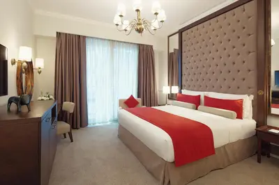 a bedroom with a large bed and a large window at Dukes The Palm Dubai Hotel in Dubai