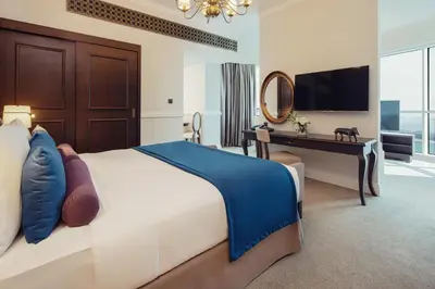 a bedroom with a bed and a desk and a television at Dukes The Palm Dubai Hotel in Dubai