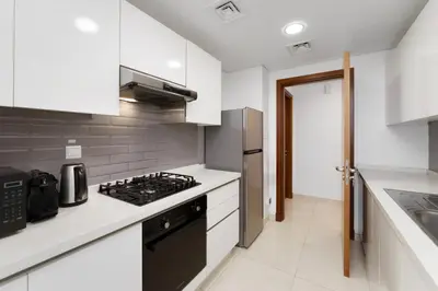 a kitchen with white cabinets and a stove top oven at Maison Privee - Modern Business Bay Retreat with Dubai Canal Views in Dubai