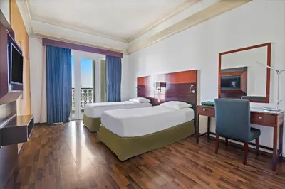 a hotel room with two beds and a desk at Al Khoory Hotel Apartments Al Barsha in Dubai