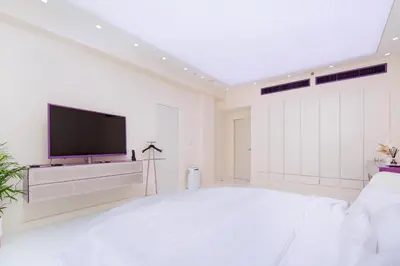 a white bedroom with a large bed and a flat screen tv at JBR Luxury Penthouse with private pool, cinema, gym, spa etc in Dubai