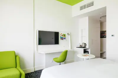 a room with a bed and a green chair at Park Inn by Radisson Dubai Motor City in Dubai