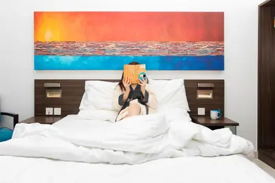 a woman laying in bed reading a book at Citymax Hotel Al Barsha at the Mall in Dubai