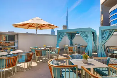 a patio with tables and chairs and an umbrella at Residence Inn by Marriott Sheikh Zayed Road, Dubai in Dubai