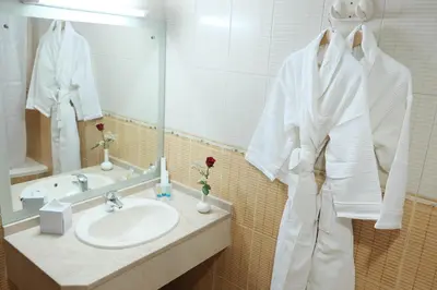 a bathroom with a sink and a white robe at Baity Hotel Apartments in Dubai