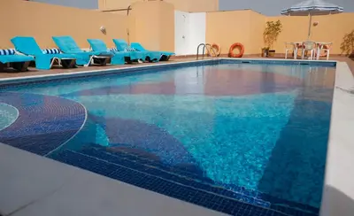 a large swimming pool with blue chairs in a building at Baity Hotel Apartments in Dubai