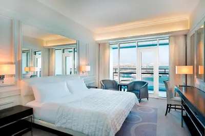 a bedroom with a bed and a desk and windows at Le Meridien Mina Seyahi Beach Resort & Waterpark in Dubai