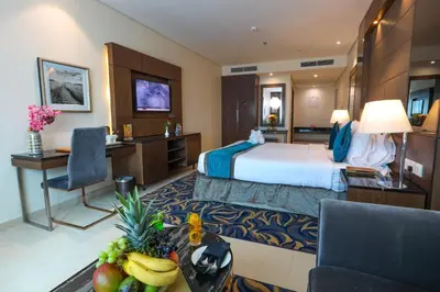 a hotel room with a bed and a table with fruit on it at Omega Hotel Dubai in Dubai