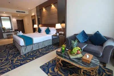 a hotel room with a bed and a couch and a table at Omega Hotel Dubai in Dubai
