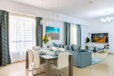a dining room with a table and a blue couch at Maison Privee - Premium Apt in the Heart of JBR Beach, Dubai in Dubai