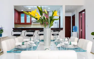 a dining room with a table with yellow flowers in a vase at Maison Privee - Premium Apt in the Heart of JBR Beach, Dubai in Dubai