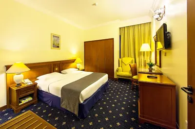 a hotel room with a large bed and a chair at Rolla Residence Hotel Apartment in Dubai