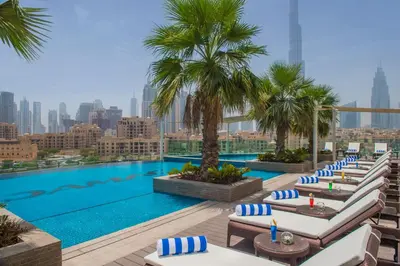 a pool with lounge chairs and palm trees on a building at DAMAC Maison Distinction in Dubai