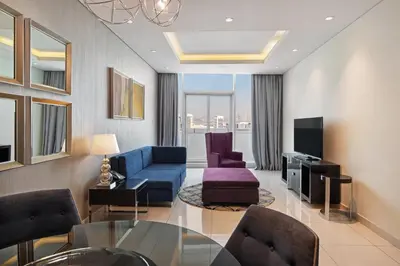 a living room with a blue couch and chairs at DAMAC Maison Distinction in Dubai