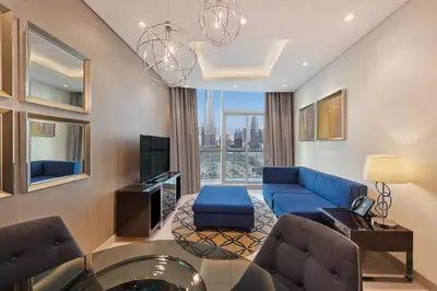 a living room with a blue couch and a tv at DAMAC Maison Distinction in Dubai
