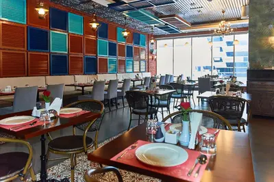 a dining room with tables and chairs in a restaurant at Rose Park Hotel - Al Barsha, Opposite Metro Station in Dubai