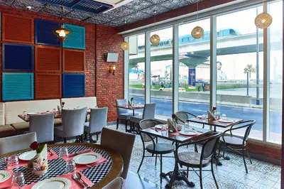 a dining room with tables and chairs and windows at Rose Park Hotel - Al Barsha, Opposite Metro Station in Dubai
