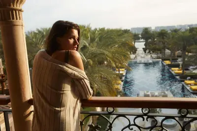 a woman standing on a balcony looking out at a pool at One&Only The Palm Dubai in Dubai