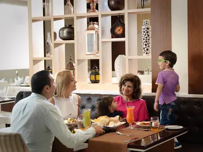 a family sitting at a table eating at a restaurant at Two Seasons Hotel & Apartments in Dubai
