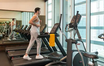 a man walking on a treadmill in a gym at voco - Bonnington Dubai by IHG in Dubai