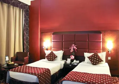 a hotel room with two beds and a chair at Ramee Rose Hotel in Dubai