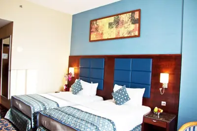 two beds in a hotel room with a blue wall at Ramee Rose Hotel in Dubai
