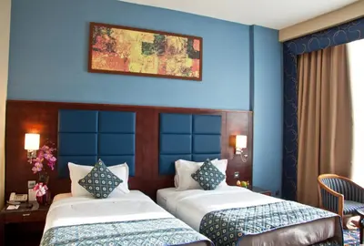 two beds in a room with blue walls at Ramee Rose Hotel in Dubai