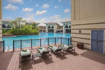 a balcony with a table and chairs and a swimming pool at Jumeirah Zabeel Saray Dubai in Dubai