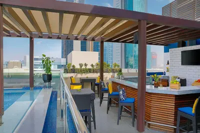 a rooftop patio with a bar and tables and chairs at voco Dubai by IHG in Dubai